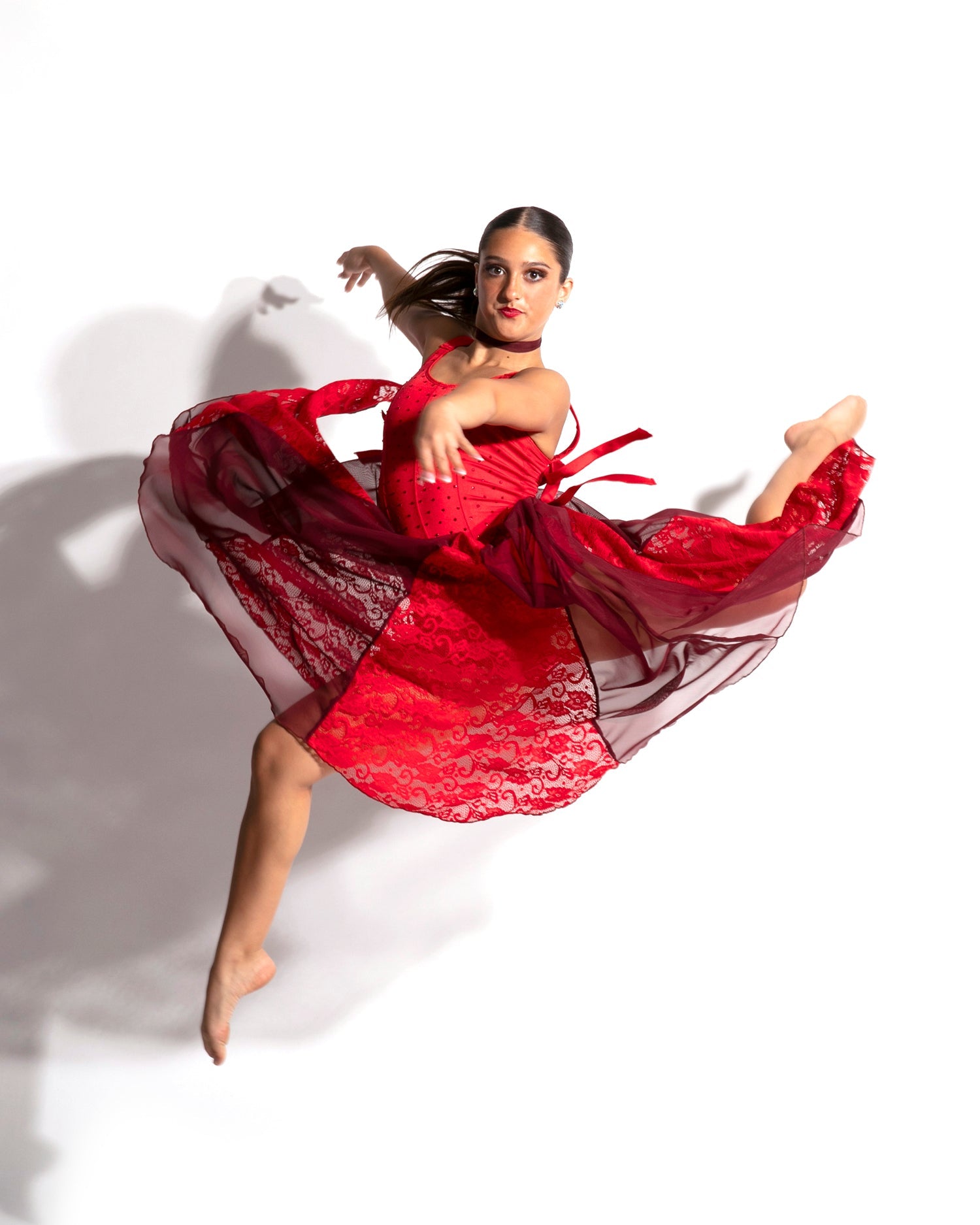 Dancer jumping in black, green, and blue biketard with mesh cutouts.