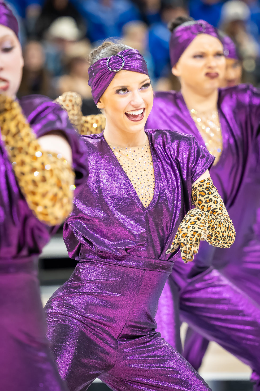Dancers in purple costumes with gold accents performing on stage.